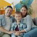 Portrait of cheerful young people woman, man and child smiling laughing sitting on couch in apartment and looking at camera. Family and emotions concept.